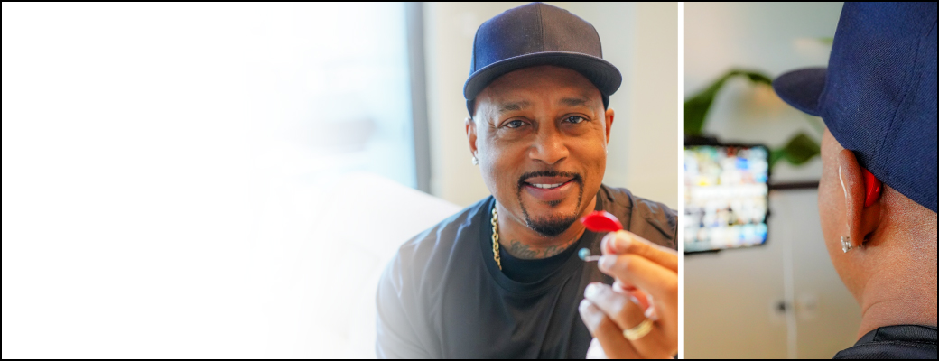 Image of Shark Tank co-star Daymond John holding up his red hearing aid
